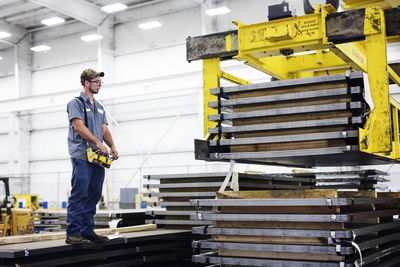 Worker operating overhead crane in metal steel mill