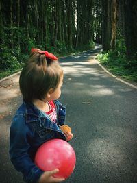 Girl with ball standing on road