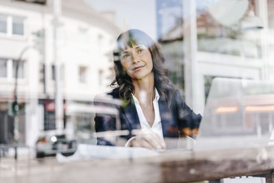 Businesswoman sitting in cafe, daydreaming