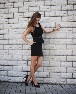 Portrait of young woman standing on brick wall