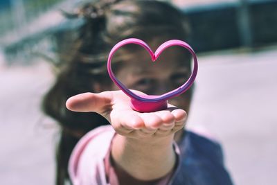 Portrait of girl showing heart shape during sunny day