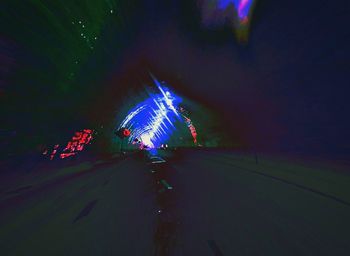Illuminated ferris wheel on road at night