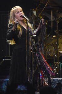 Young woman with arms raised at music concert