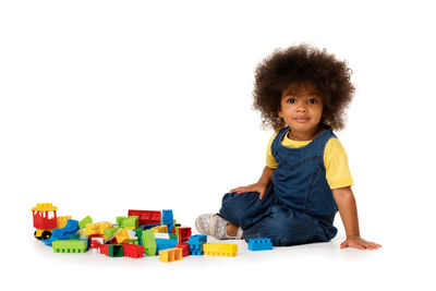 Portrait of cute boy playing with toy against white background
