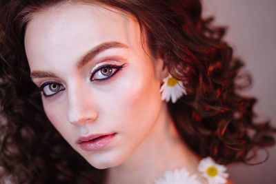 Close-up portrait of beautiful young woman wearing flowers and make-up
