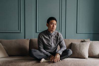 Young woman sitting on sofa at home