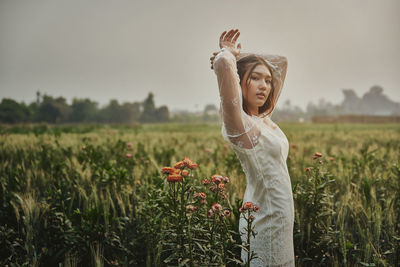Portrait of girl standing by flowering plants against sky