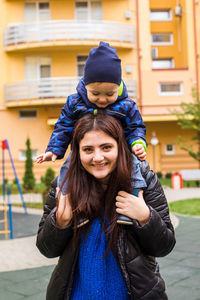 Mother carrying daughter on shoulder at park