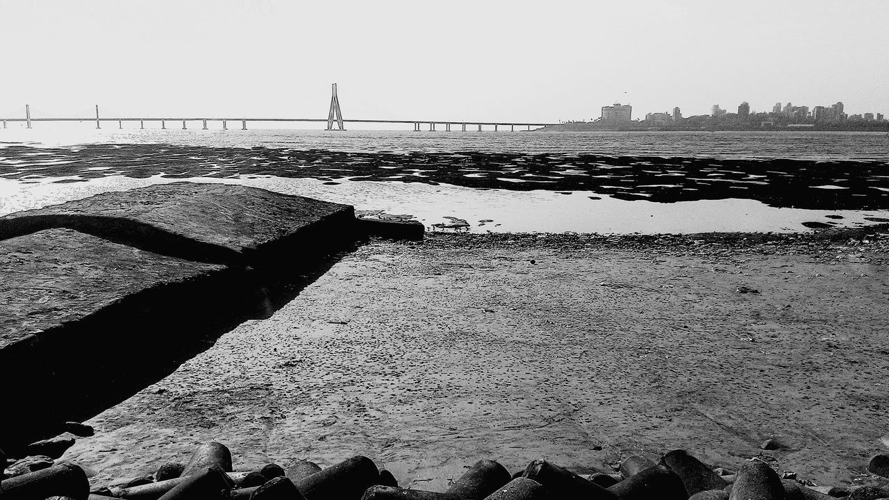 water, sea, built structure, architecture, building exterior, clear sky, sky, river, outdoors, nature, railing, pier, silhouette, day, no people, sunlight, city, copy space, protection, tranquility