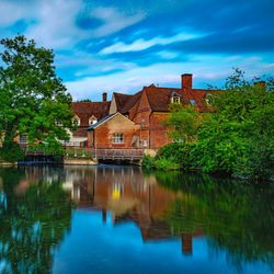 Houses by lake and buildings against sky