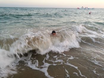 Man surfing in sea against sky