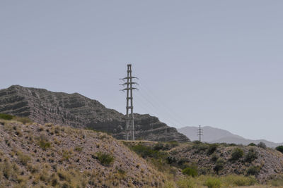 Electricity pylon on land against sky