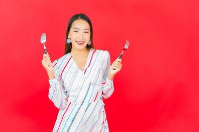 Portrait of a smiling young woman against red background