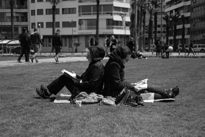 People sitting on sidewalk in city