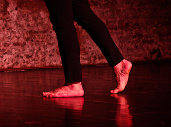 Low section of woman standing on pink floor