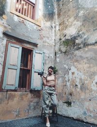 Full length portrait of woman standing against building