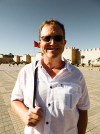 Portrait of smiling man wearing sunglasses against clear sky