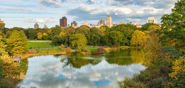 Scenic view of lake by trees and buildings against sky