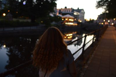 Rear view of woman standing by river in city