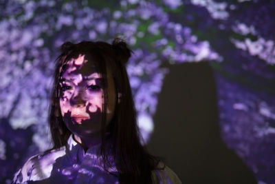 Portrait of woman looking at purple flower