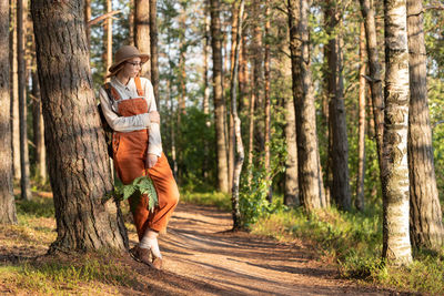 Woman botanist with backpack on ecological hiking trail in forest. naturalist exploring wildlife