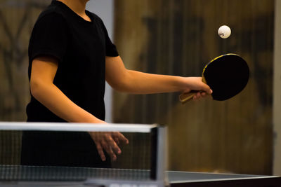Midsection of boy playing table tennis
