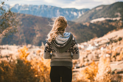 Rear view of woman standing on mountain against sky