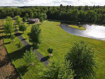 Beautiful and rural country home with a long driveway and pond surrounded by forests.