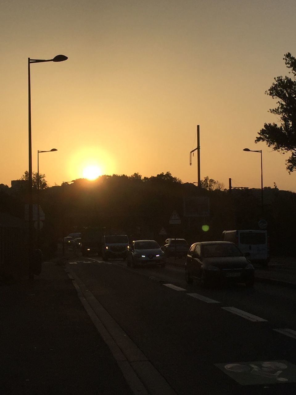 CARS ON ROAD AGAINST SKY AT SUNSET