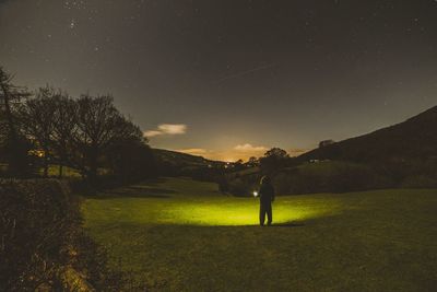 Full length of person standing on grassy field against star field