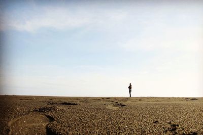 Surface level shot of man standing at beach against sky