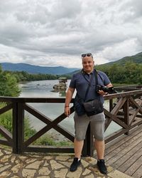 Full length of man standing on railing against sky