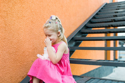 Side view of young woman standing against escalator