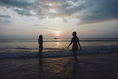 Silhouette men standing on beach against sky during sunset