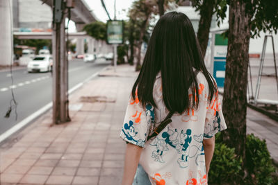 Rear view of woman standing on footpath