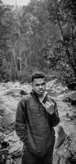 Portrait of young man gesturing while standing in forest