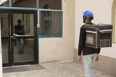 Rear view of young man standing against building