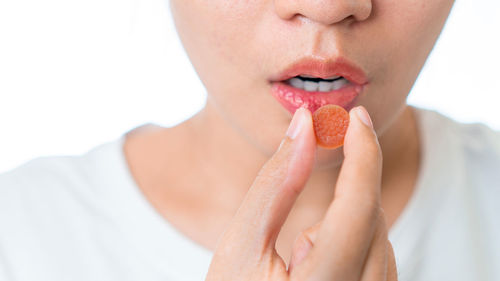 Close-up of woman eating ice cream over white background