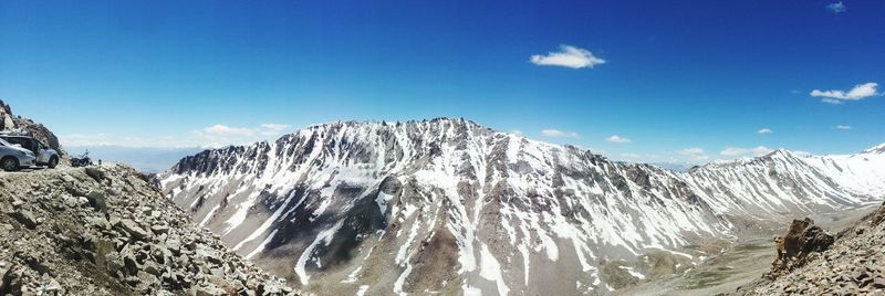 Scenic view of snow covered mountains against blue sky