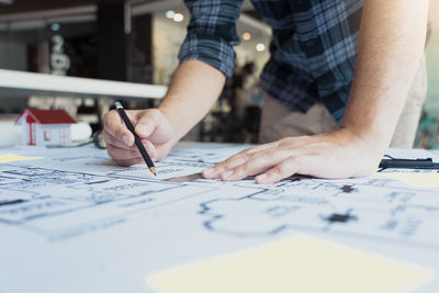 Midsection of man holding paper on table