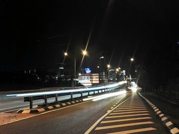 Illuminated road against sky at night