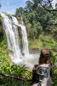 Rear view of woman standing against waterfall