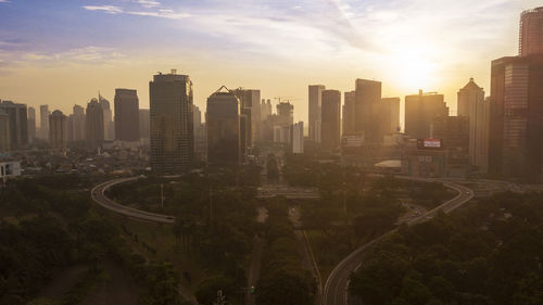 Aerial view of modern buildings in city against sky during sunset