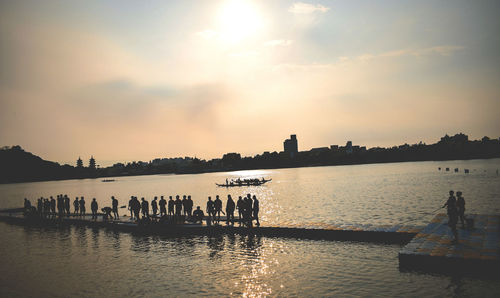 Silhouette people on boat in river against sky during sunset