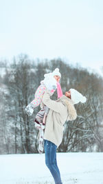 Woman standing on snow field against trees during winter