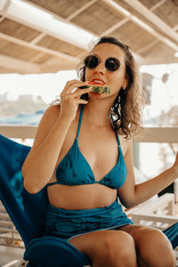 Portrait of a young woman sitting and eating watermelon