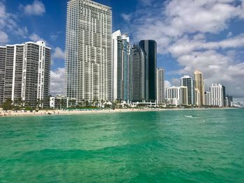 Modern buildings by sea against sky in city