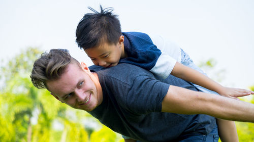 Father playing with son at park against clear sky