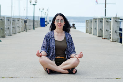 Portrait of young woman sitting on footpath