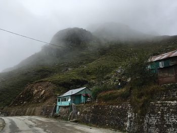 Road by buildings against sky